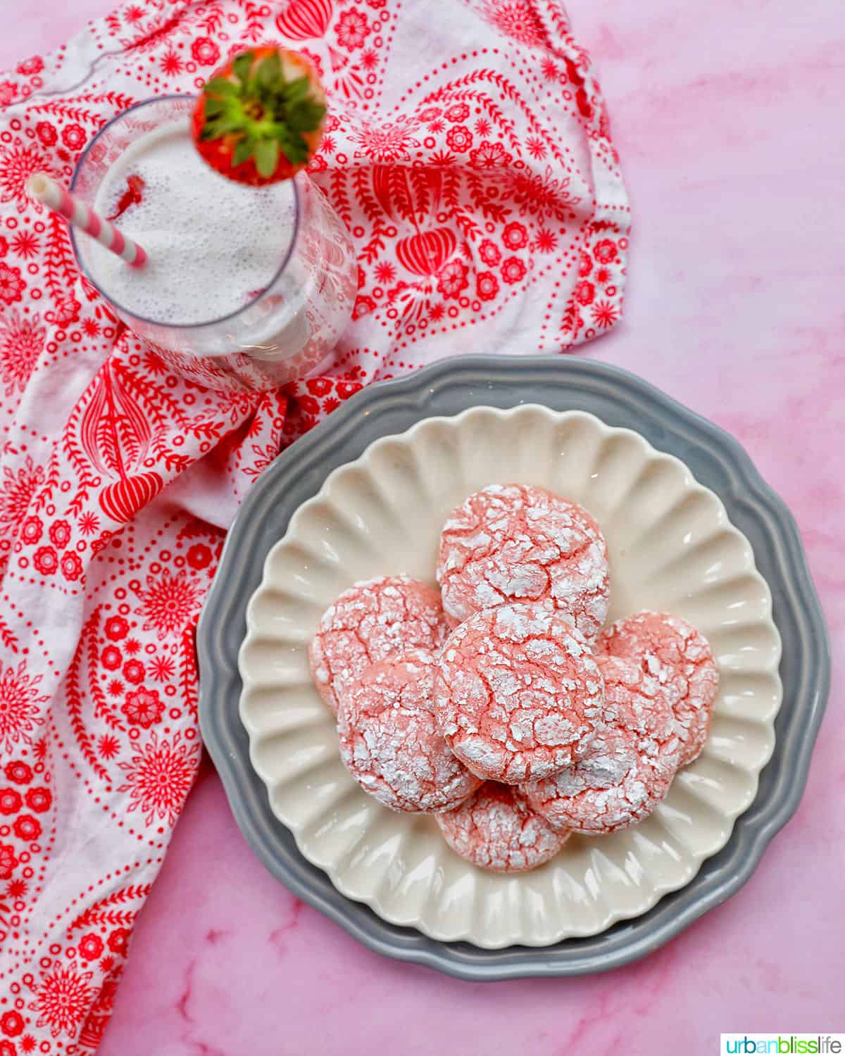 plate of baked strawberry crinkle cookies with glass of strawberry milk