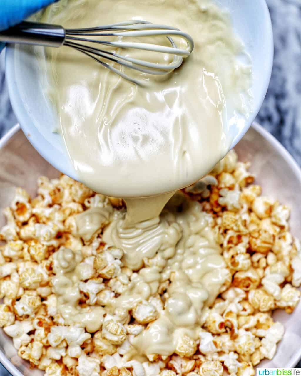 pouring melted white chocolate over popcorn