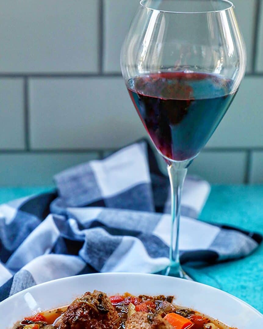 glass of red wine with bowl of meatball soup