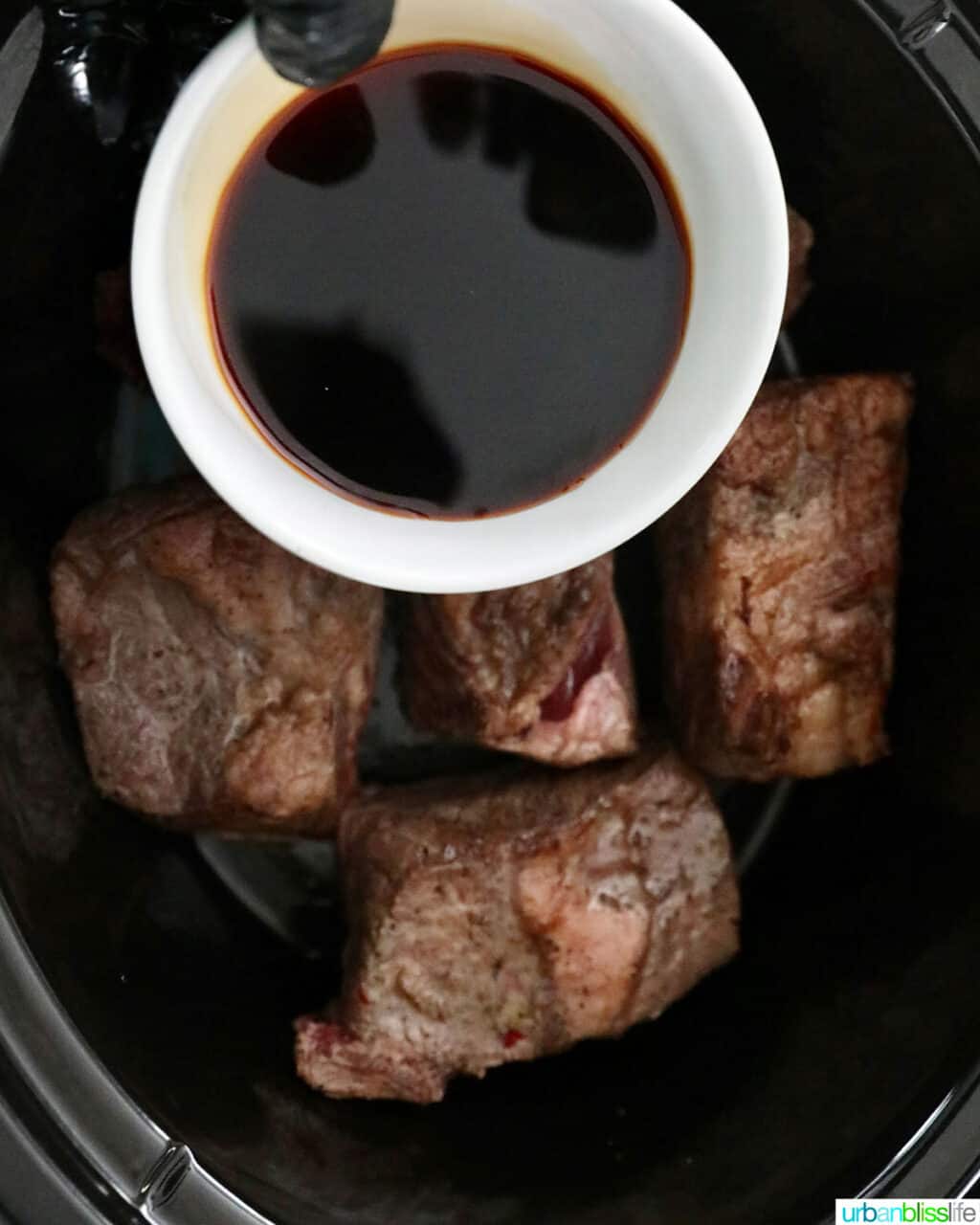 adding soy sauce to beef short ribs in the slow cooker