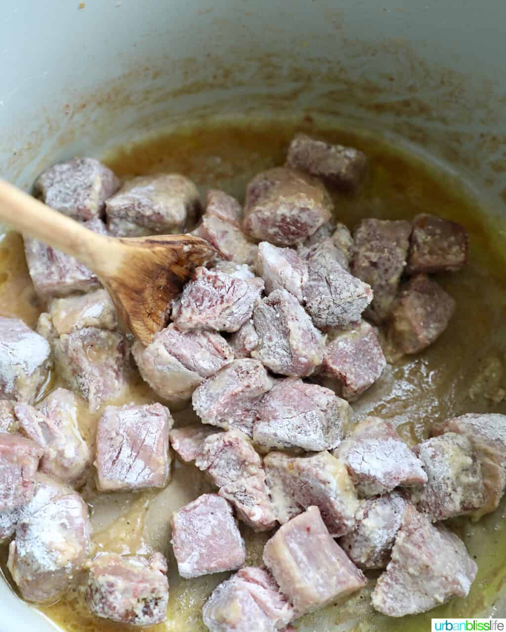 stirring the coated lamb in the pressure cooker