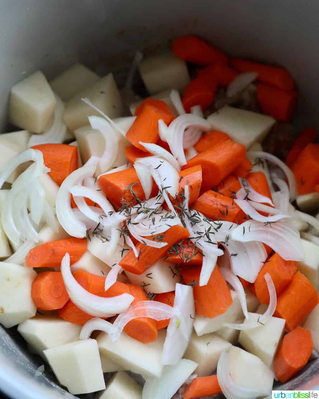 adding onions to potatoes and carrots