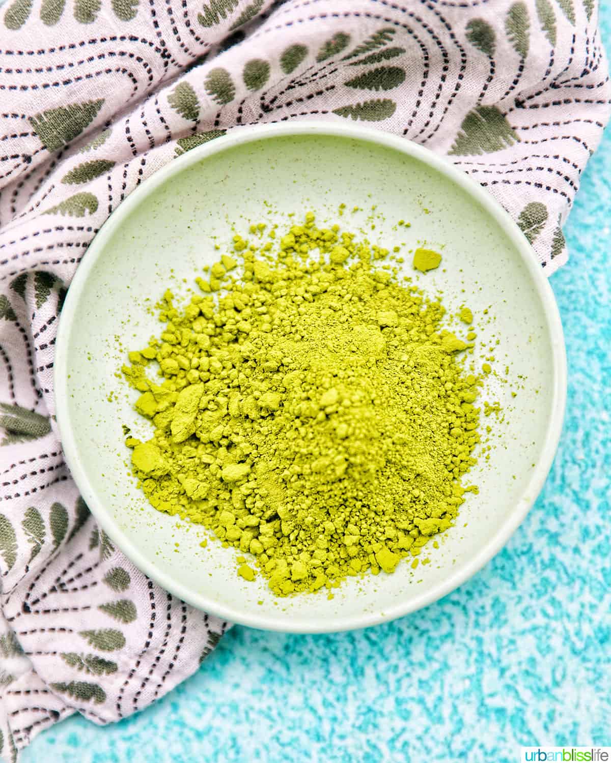 small bowl of bright green matcha green tea powder on a green and white napkin.