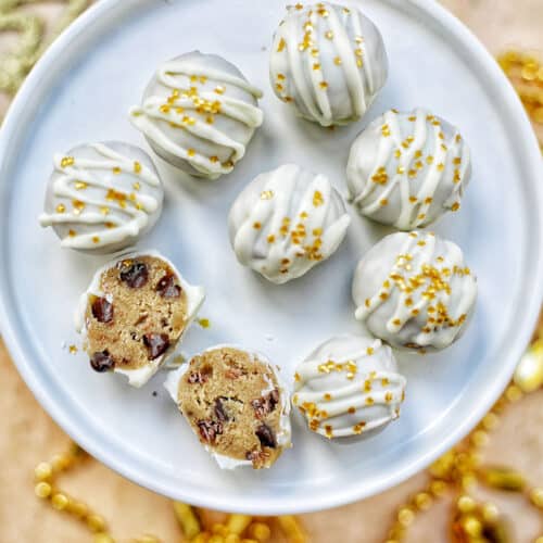 gold decorated white chocolate coated cookie dough truffles on a plate with two split open