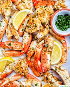 air fryer crab legs with lemon wedges and chopped parsley.