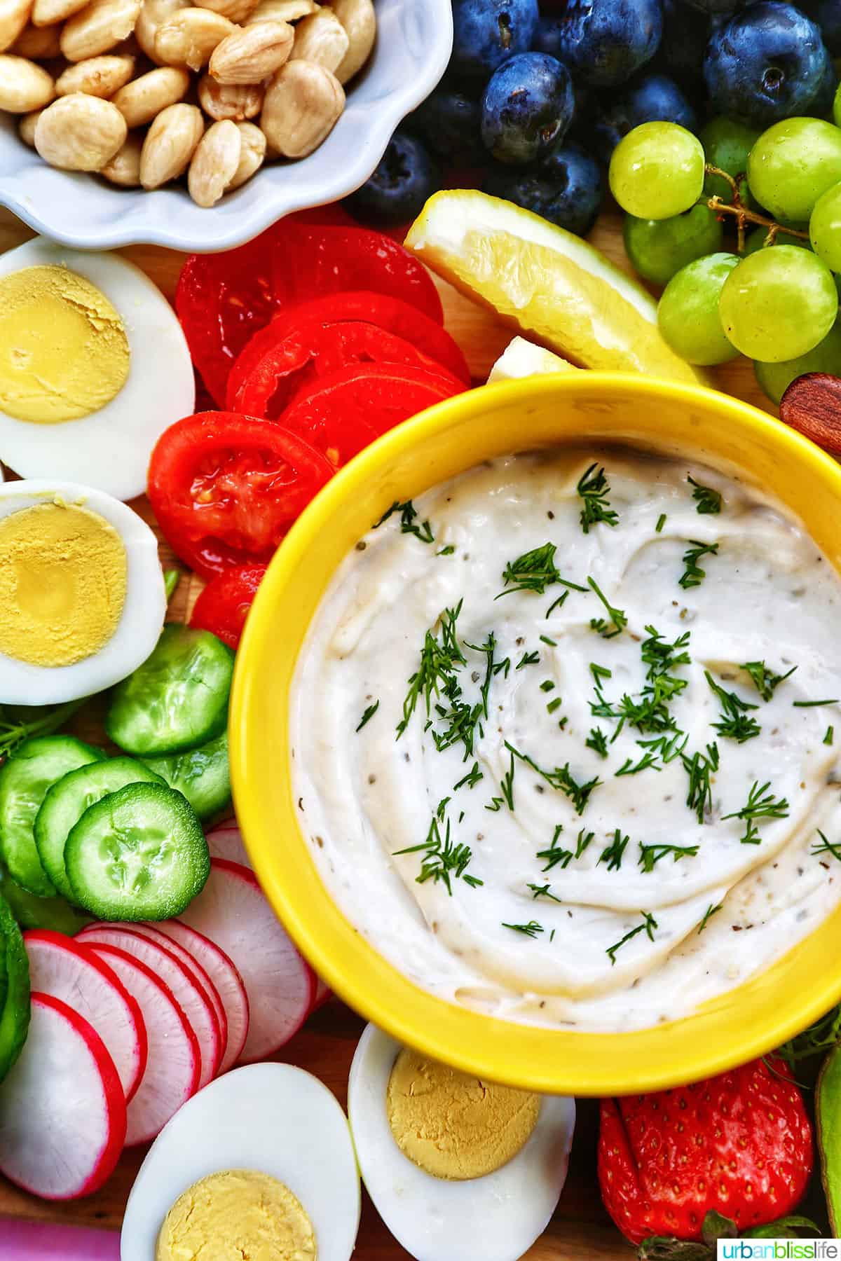 veggies and fruit surrounding dip in a bowl