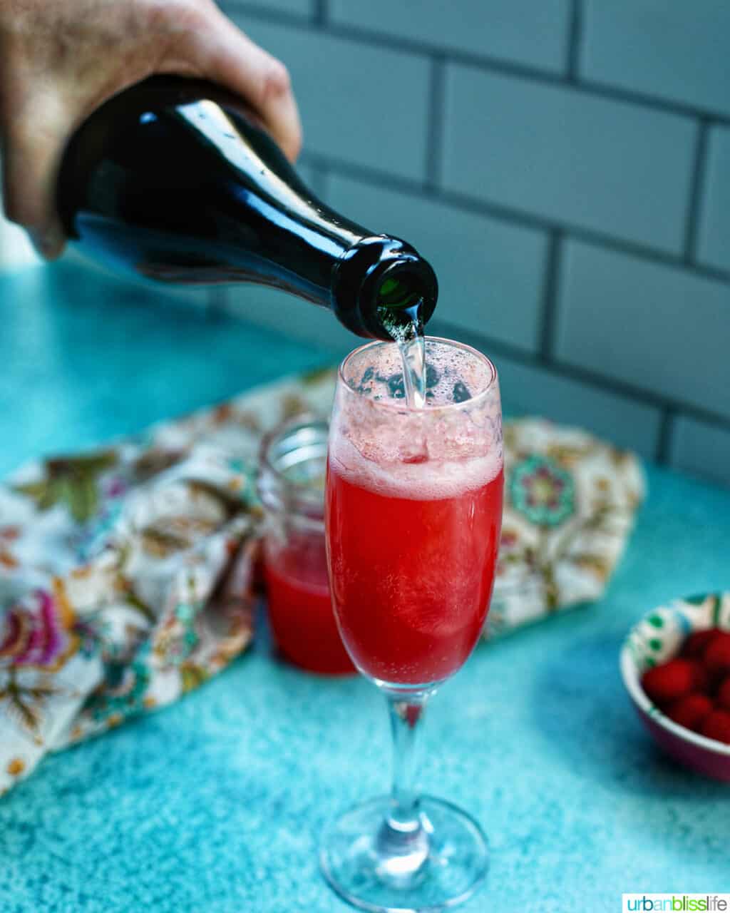 pouring sparkling wine into a glass to make Raspberry Mimosas