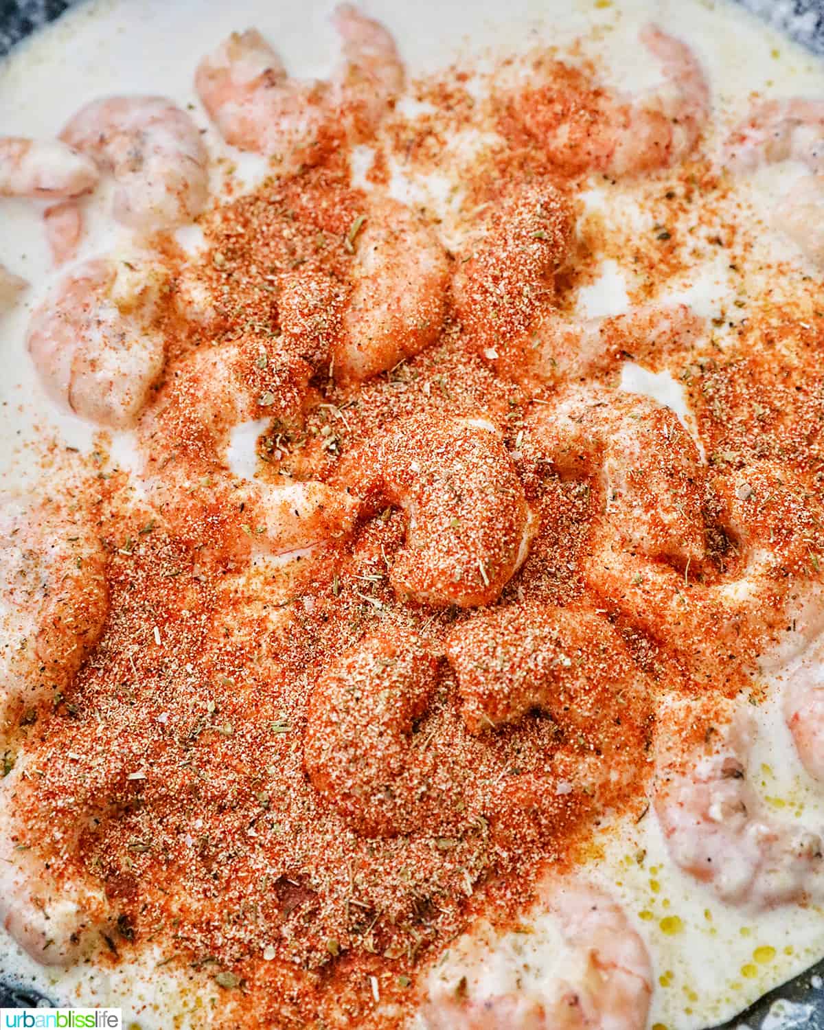 adding cajun seasoning to shrimp