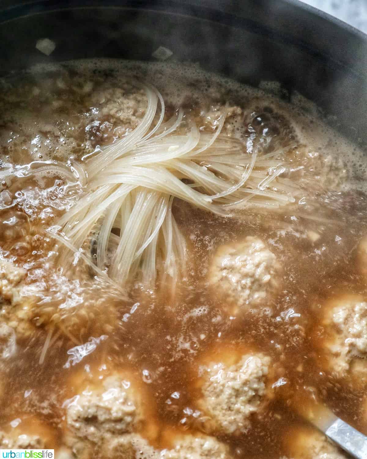 meatballs and noodles cooking in almondigas soup