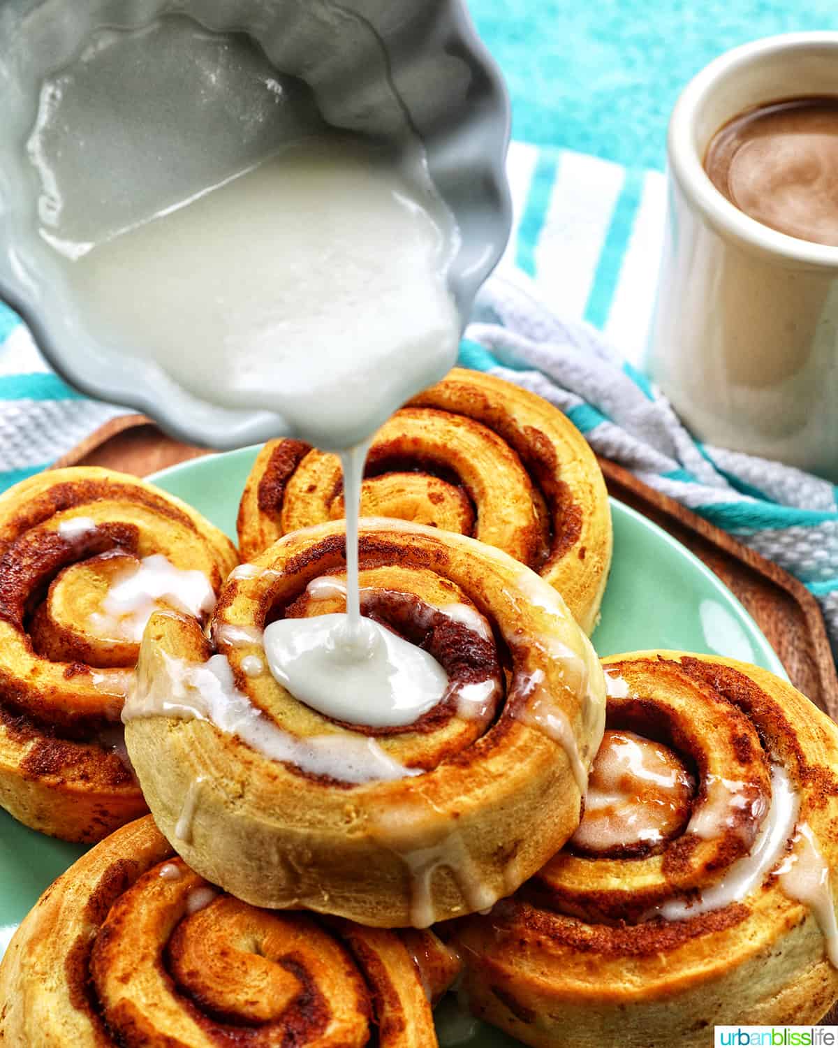 pouring icing over cinnamon rolls