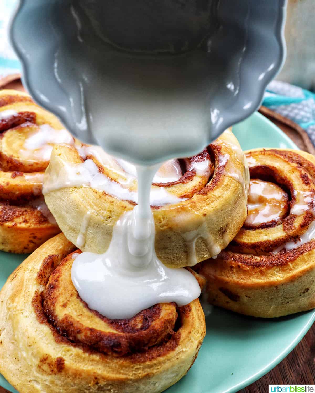 pouring icing over cinnamon rolls