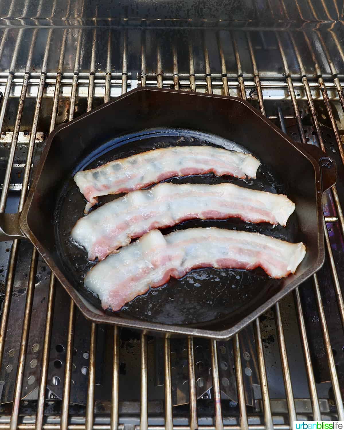 cooking bacon slices on a grill in a cast iron pan