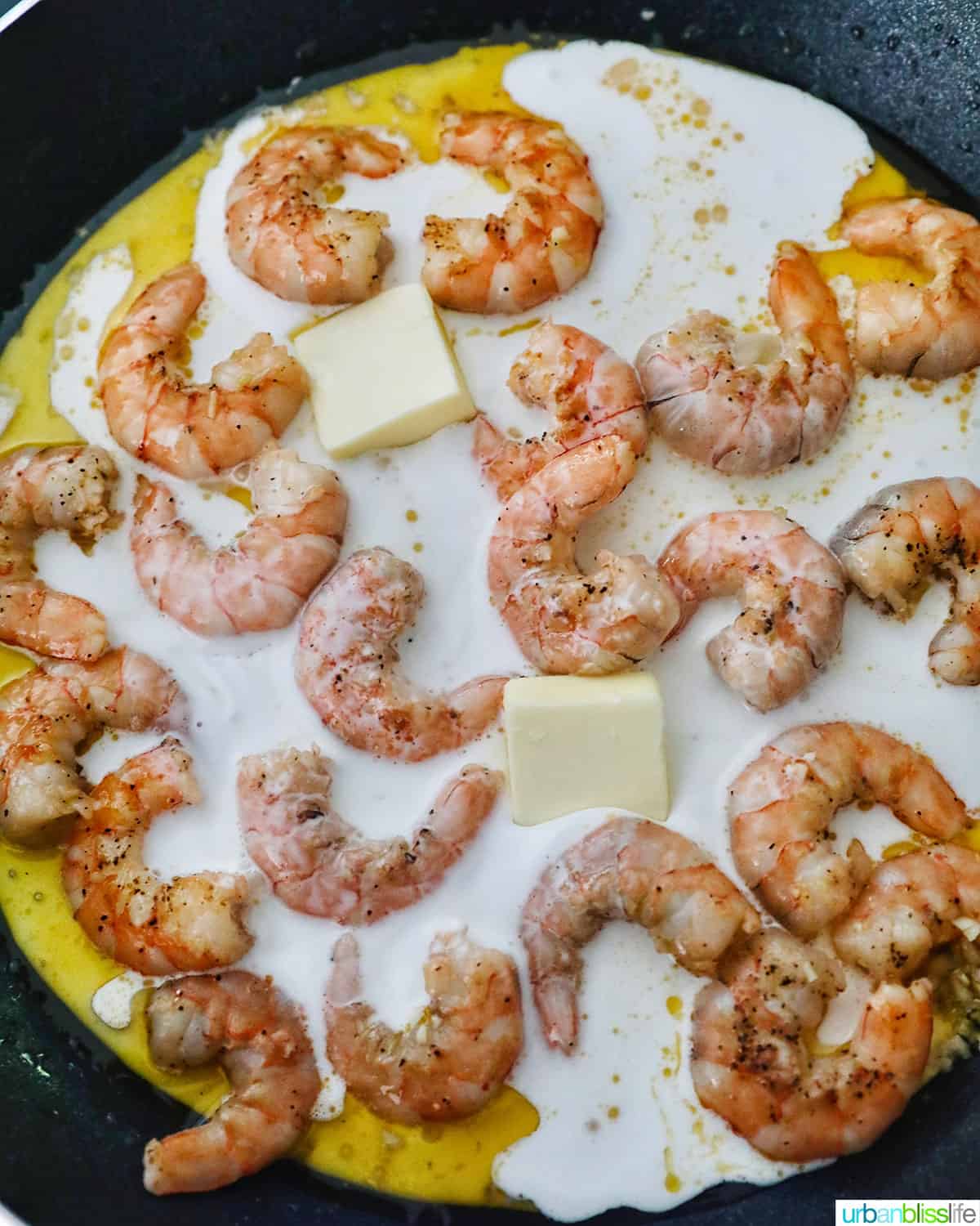adding butter to cajun shrimp pasta in the pan