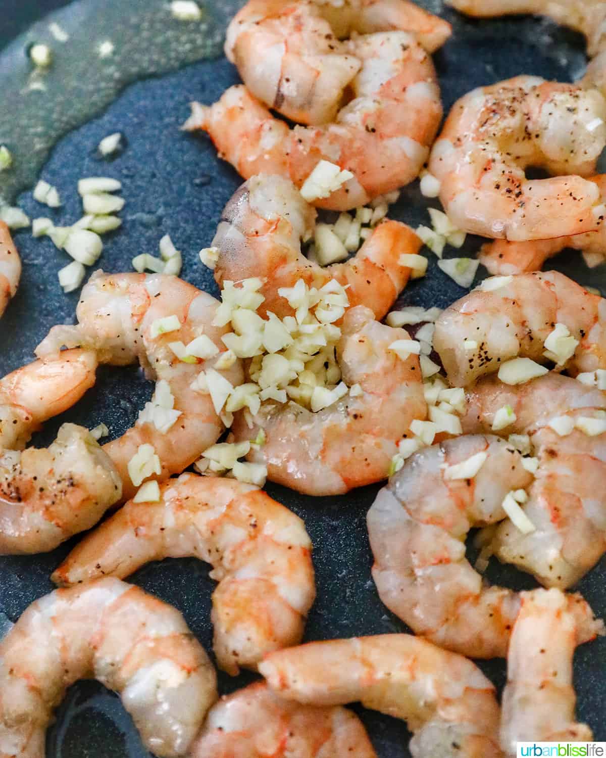 adding garlic to shrimp in the pan