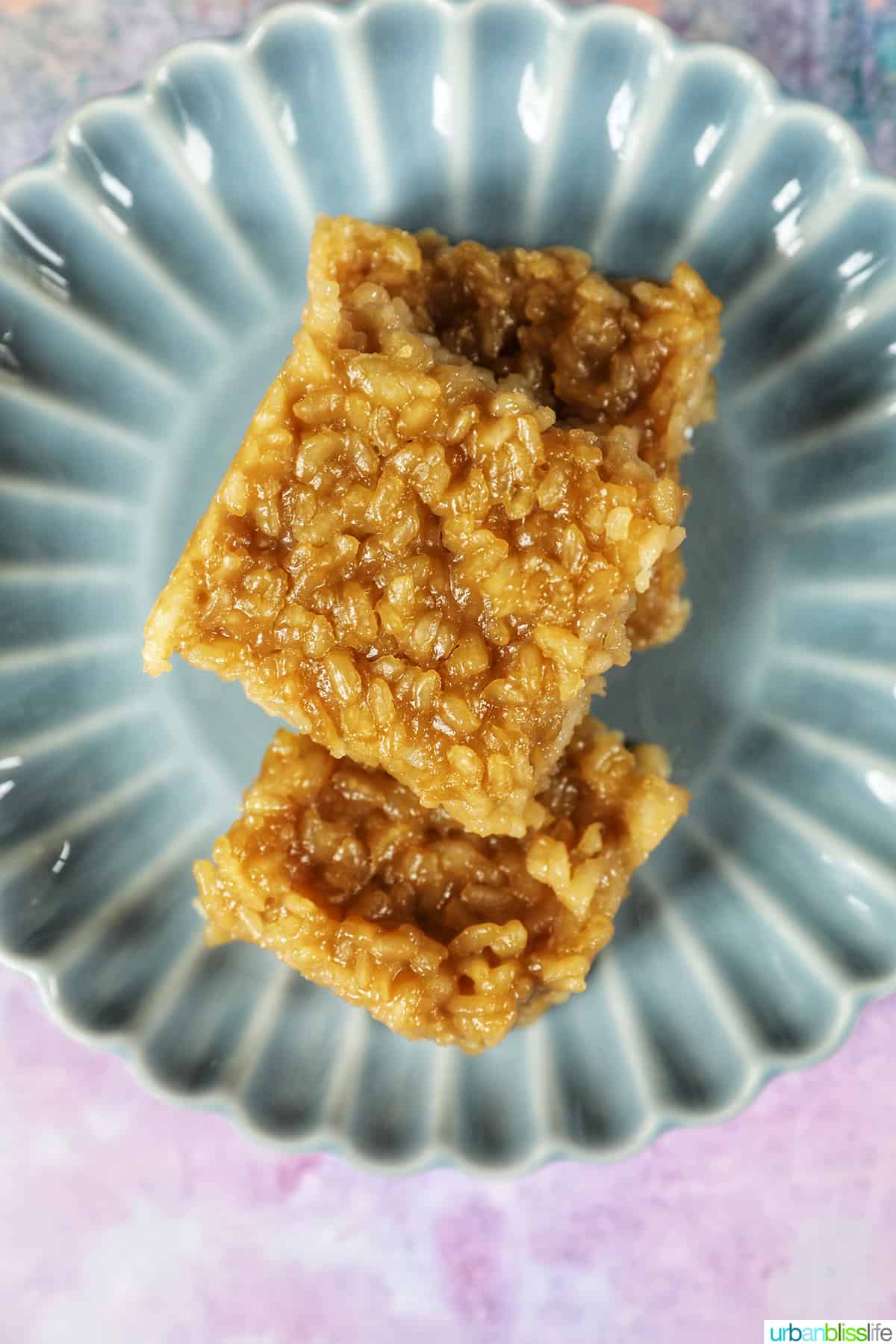 slices of filipino biko stacked on top of one another, on a blue scalloped plate.