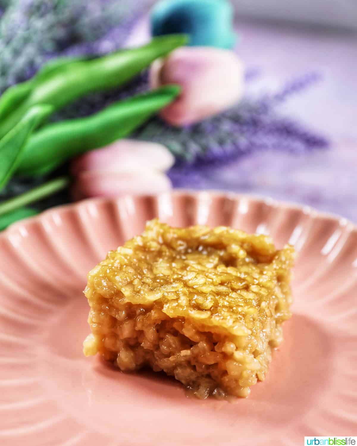 slice of filipino biko on a pink scalloped plate with flowers in the background