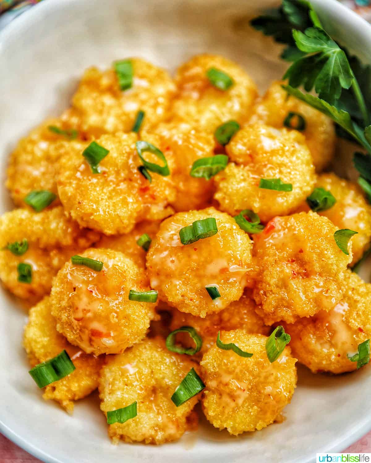 air fryer bang bang shrimp garnished with green onions in a white bowl.