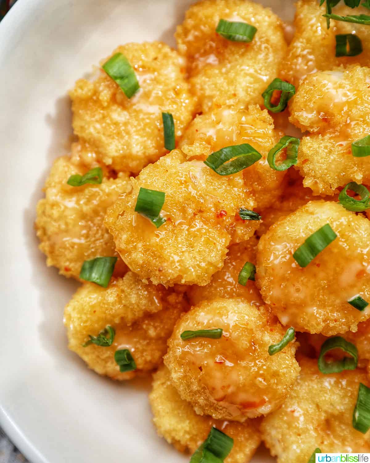 air fryer bang bang shrimp garnished with green onions in a white bowl.