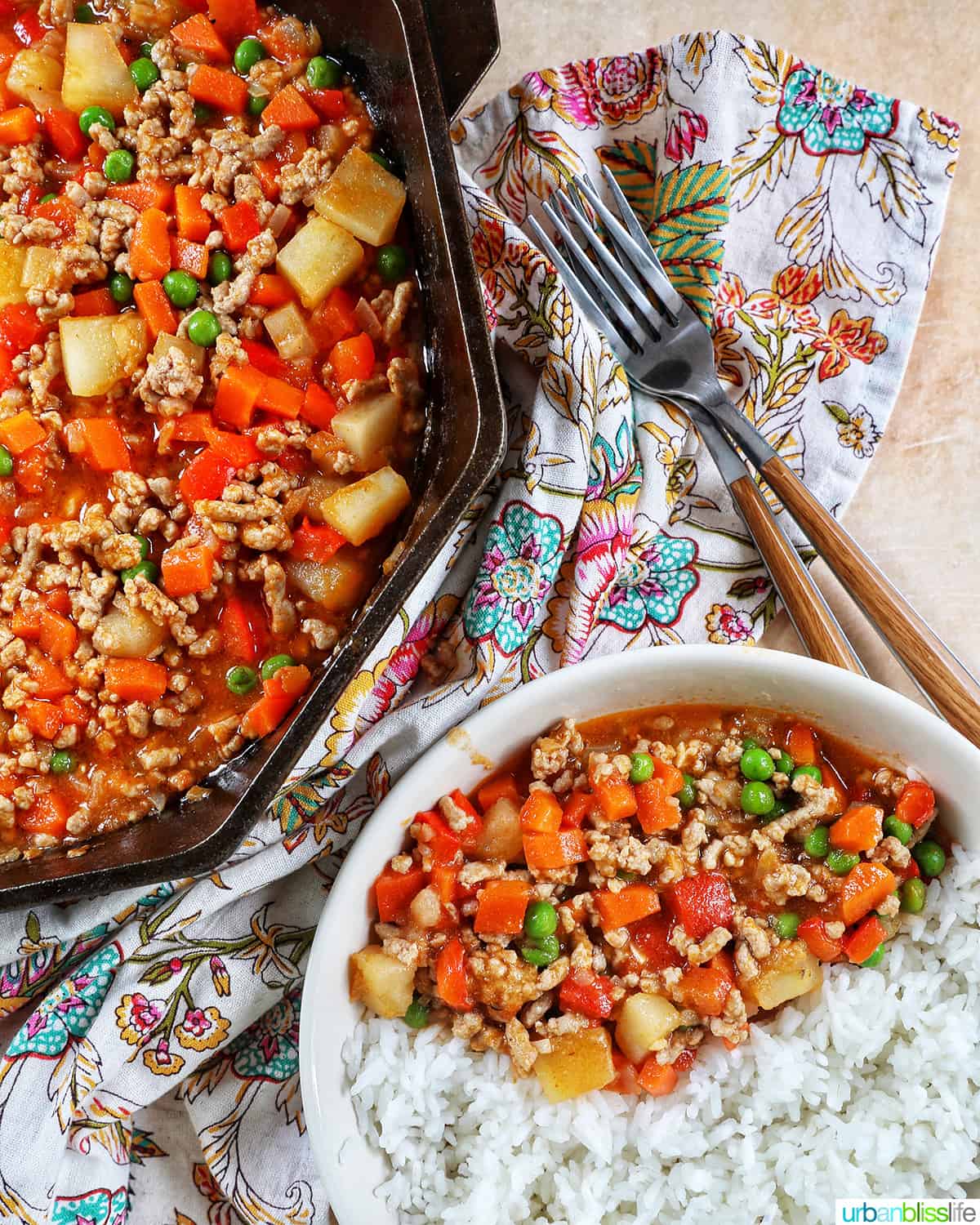 ground pork menudo in a skillet and with rice on a plate, with forks and a floral napkin.