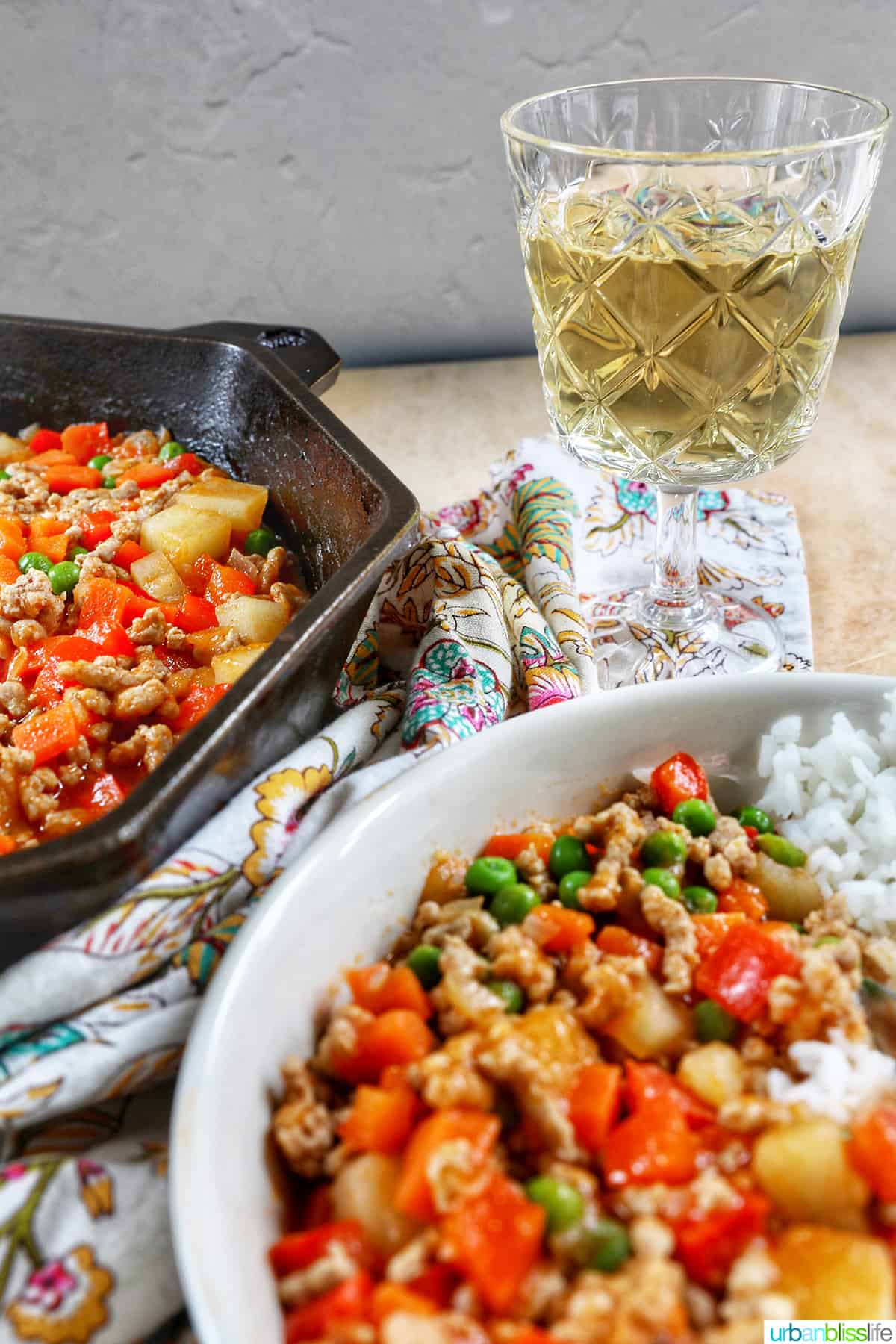 glass of white wine with skillet and bowl of ground pork menudo