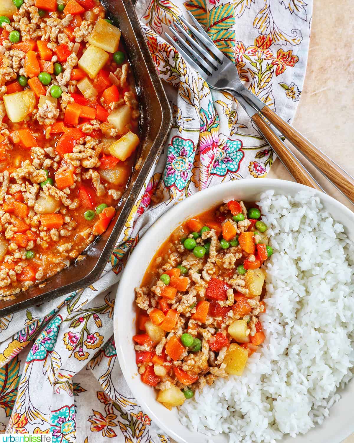 ground pork menudo in a skillet and with rice on a plate, with forks and a floral napkin.