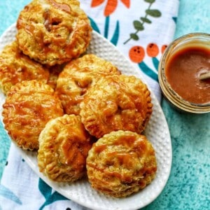 air fryer apple hand pies with caramel sauce on a platter.