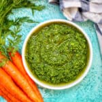 carrot top pesto in a bowl with carrots.