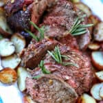 garlic rosemary sirloin tip roast with potatoes on a platter.