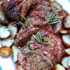 garlic rosemary sirloin tip roast with potatoes on a platter.