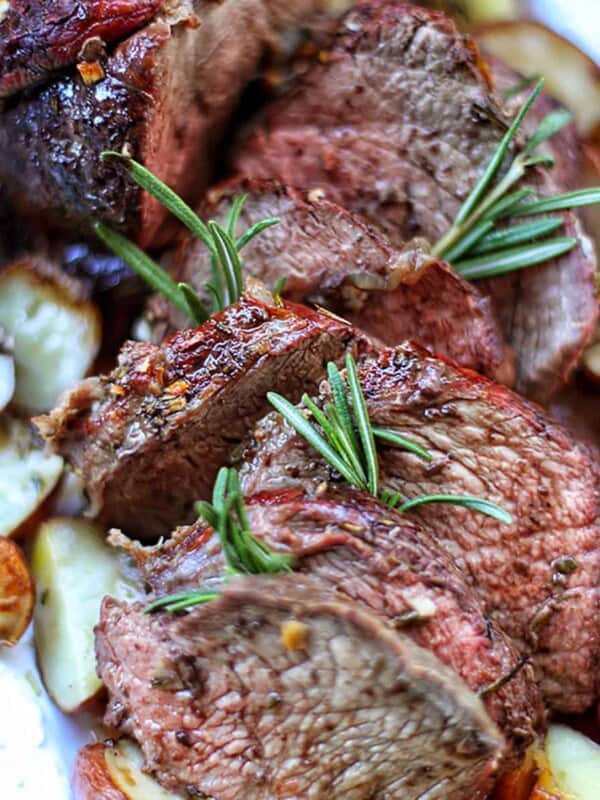 garlic rosemary sirloin tip roast with potatoes on a platter.