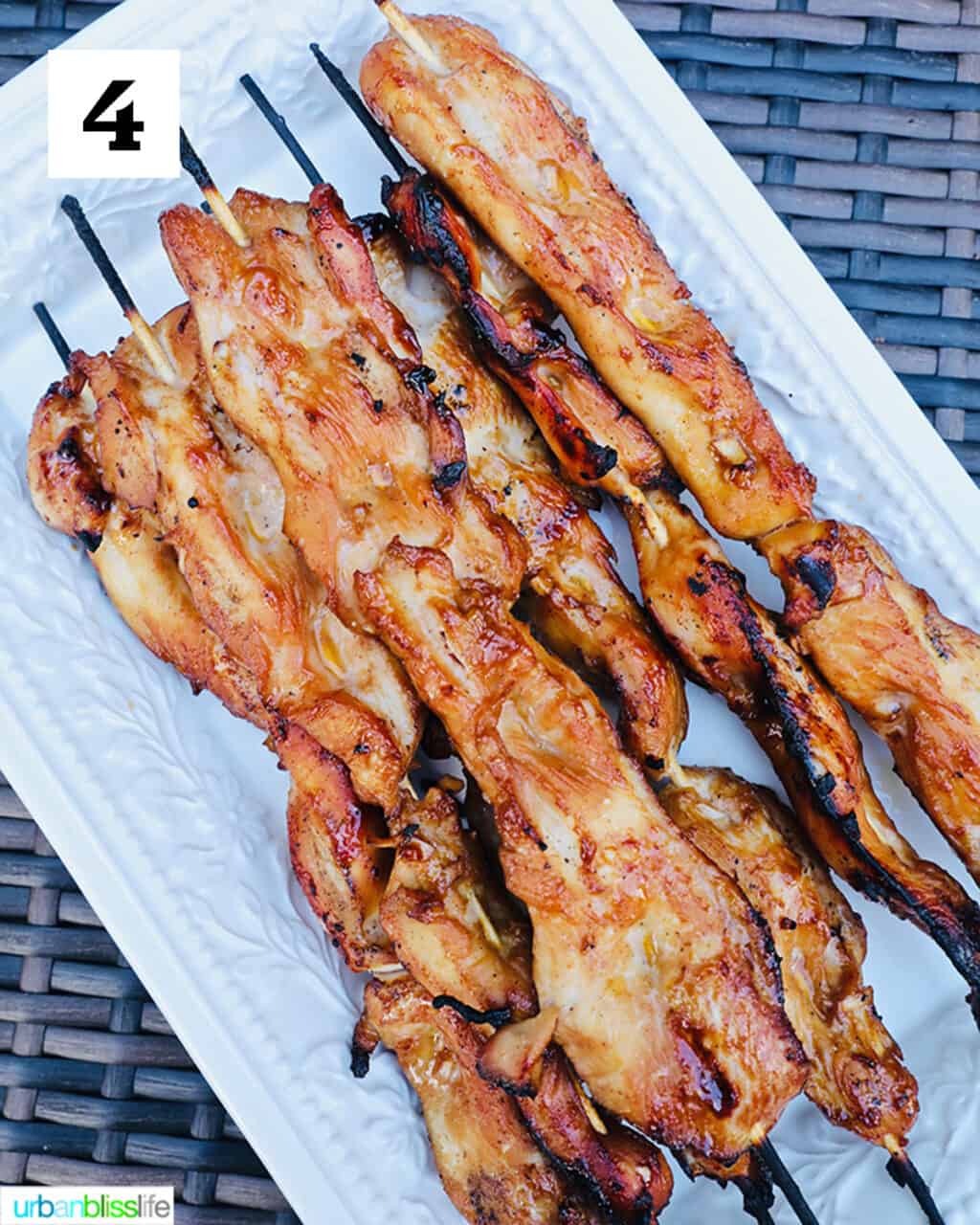honey garlic chicken skewers done grilling on white platter.
