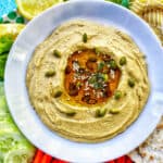 classic hummus in bowl with oil in center and pepitas.