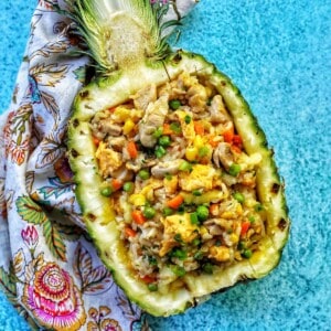 fried rice sitting in a hollowed out pineapple half.