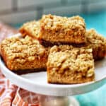 pumpkin cheesecake bars with gingersnap crust on a pedestal plate.