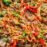 sesame garlic noodles with steak, red bell peppers, broccoli, and carrots.