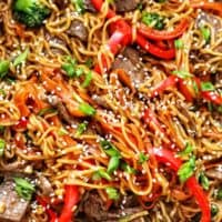 sesame garlic noodles with steak, red bell peppers, broccoli, and carrots.