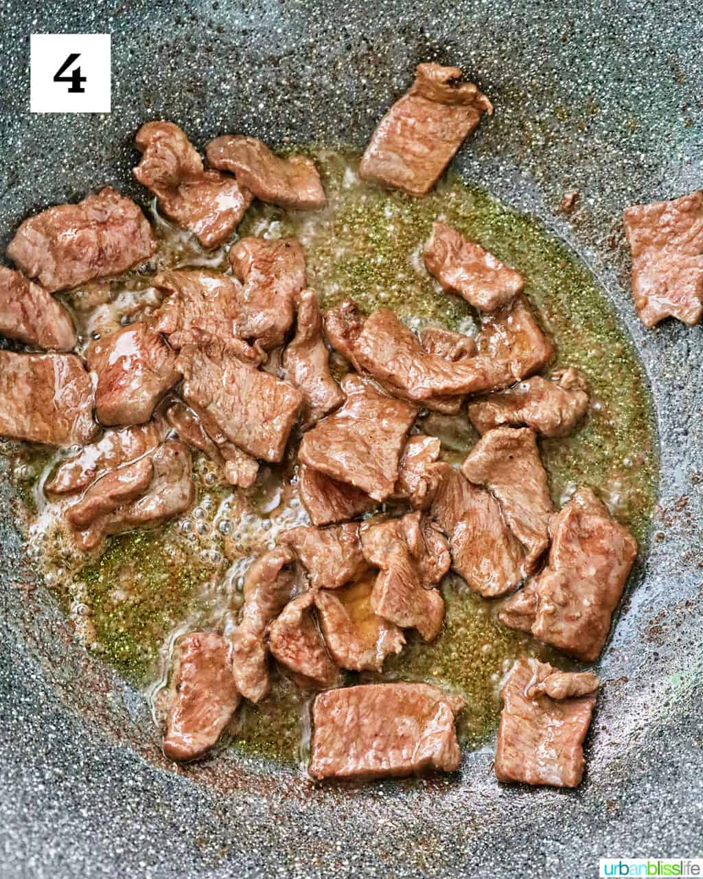 sliced steak cooking in a large wok.