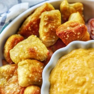 soft pretzel bites on plate next to cheese sauce.