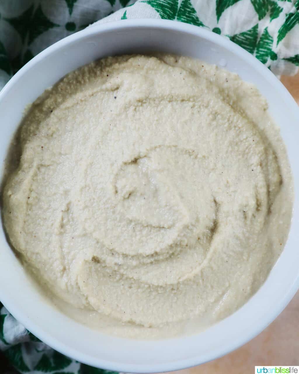 white bowl of Vegan Cashew Cheese with green and white napkin underneath.