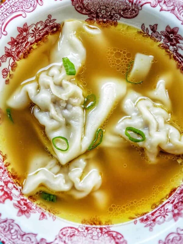 wonton noodle soup in red and white bowl.