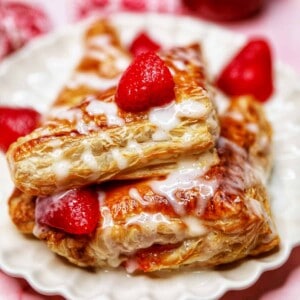 air fryer strawberry turnovers on a plate drizzled with icing.