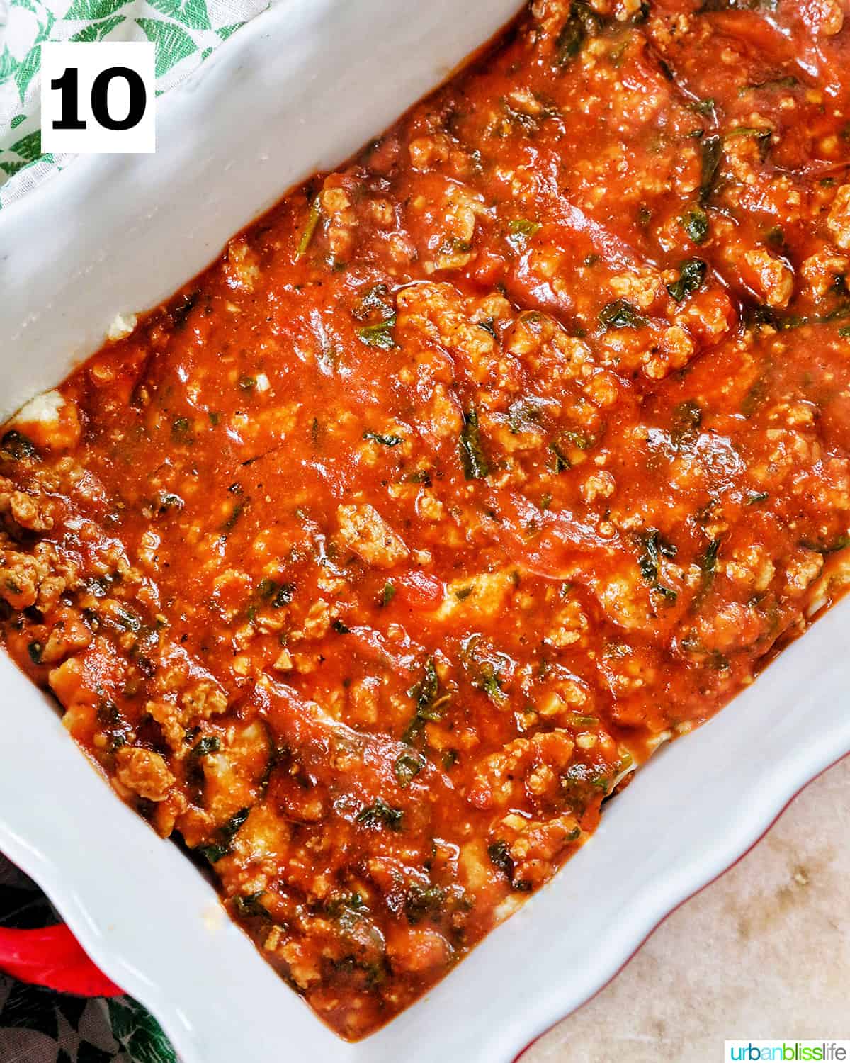 ground turkey marinara sauce in a white baking dish with red handles.
