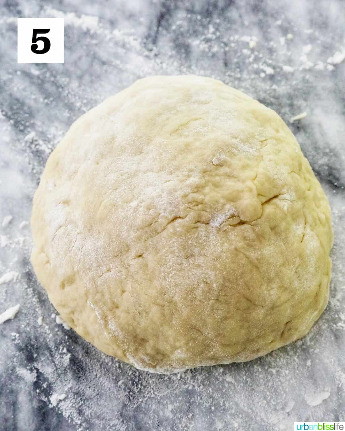dough ball on a marble countertop to make Filipino Spanish bread.