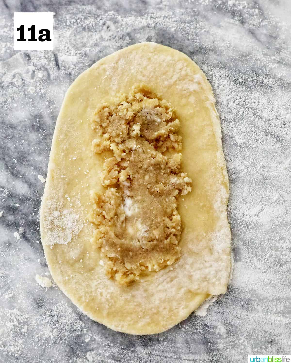 filling placed in the center of a rolled out spanish bread dough on marble countertop.