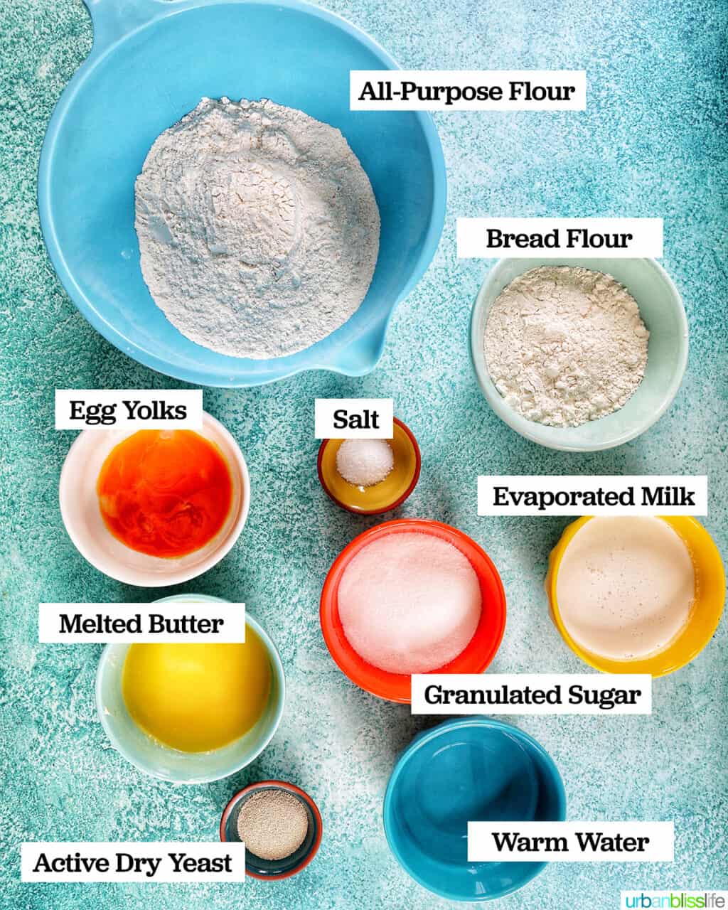 several bowls of ingredients to make Filipino Spanish bread on a blue background.