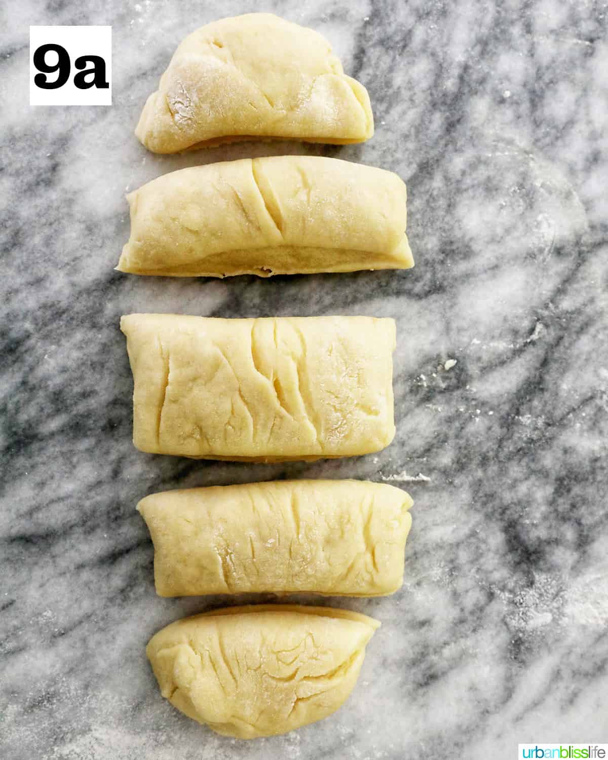 dough sliced into 5 parts on a marble countertop.