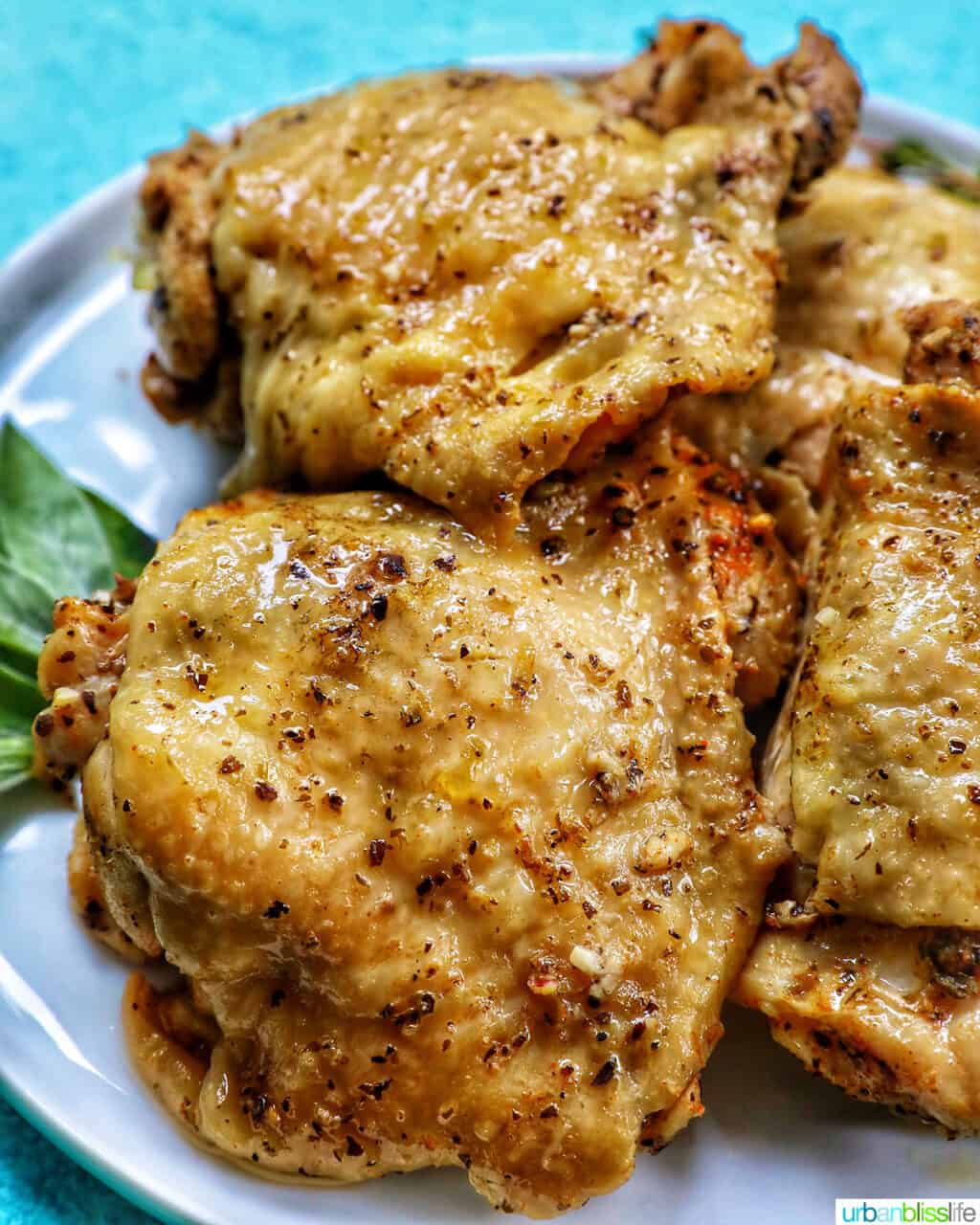 white plate with four chicken thighs and blue background