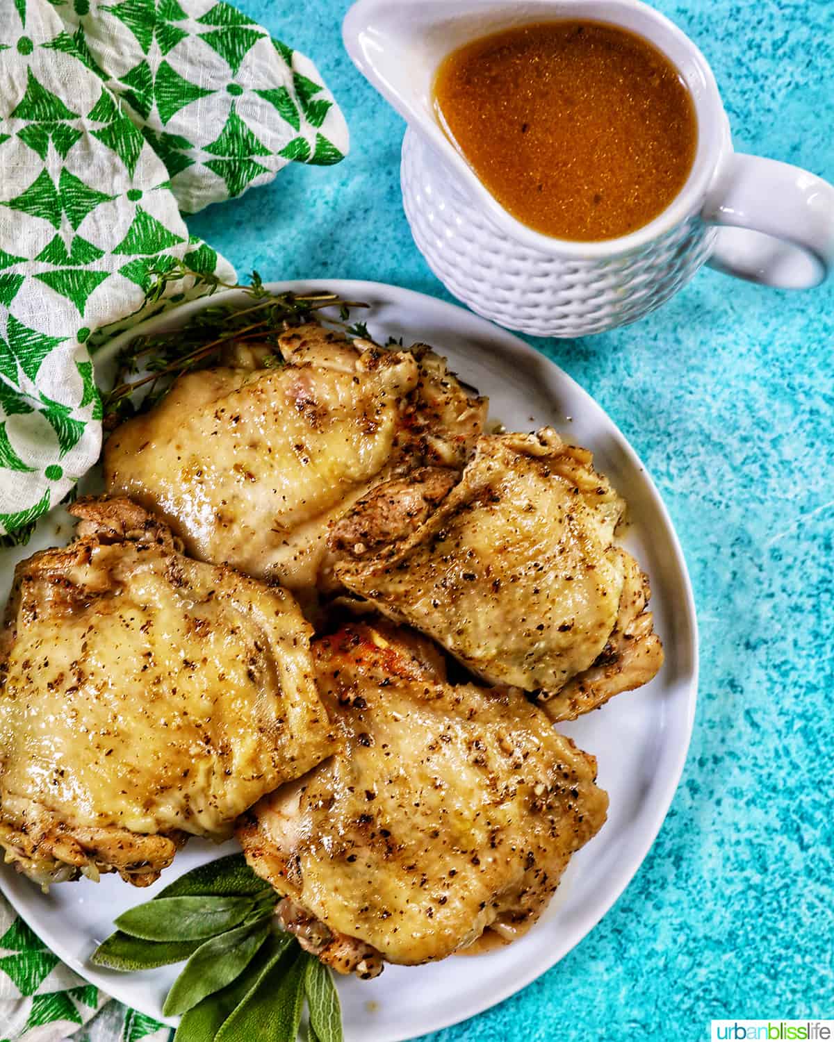 four instant pot chicken thighs on a white plate with green napkin and blue background and gravy.