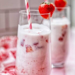 korean strawberry milk in two glasses in a red striped straw.