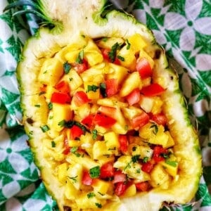 chopped pineapple, mango, tomatoes, and onions in a hollowed out pineapple.